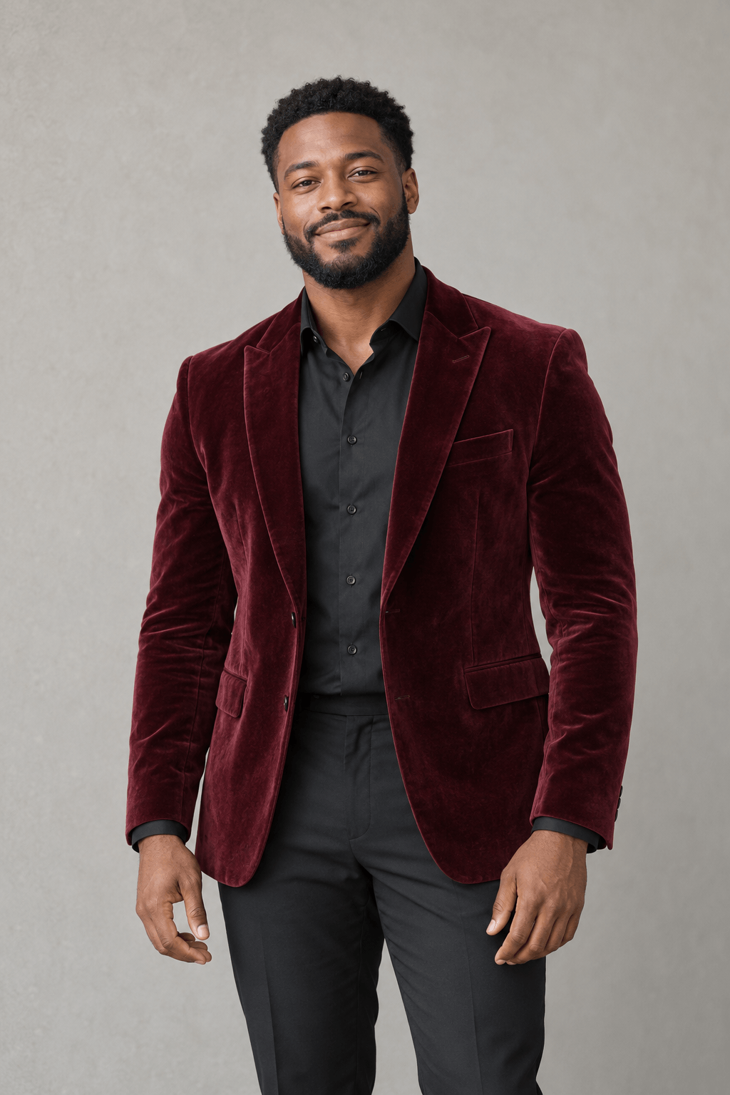 Man with short curly hair and a beard wearing a burgundy velvet jacket over a black shirt